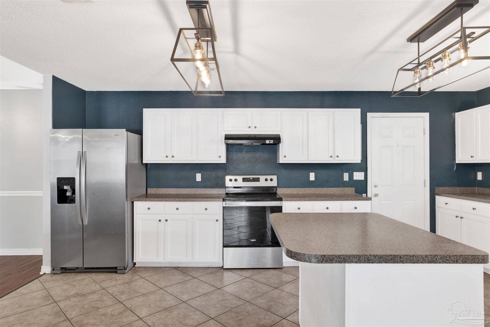 7604 Brewster Street Navarre, FL 32566 - Photo 18 of 36 a kitchen with stainless steel appliances granite countertop a sink a stove and a refrigerator