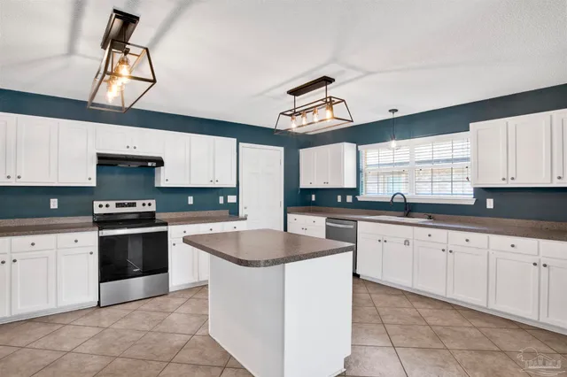 a kitchen with granite countertop white cabinets white appliances a sink and a window