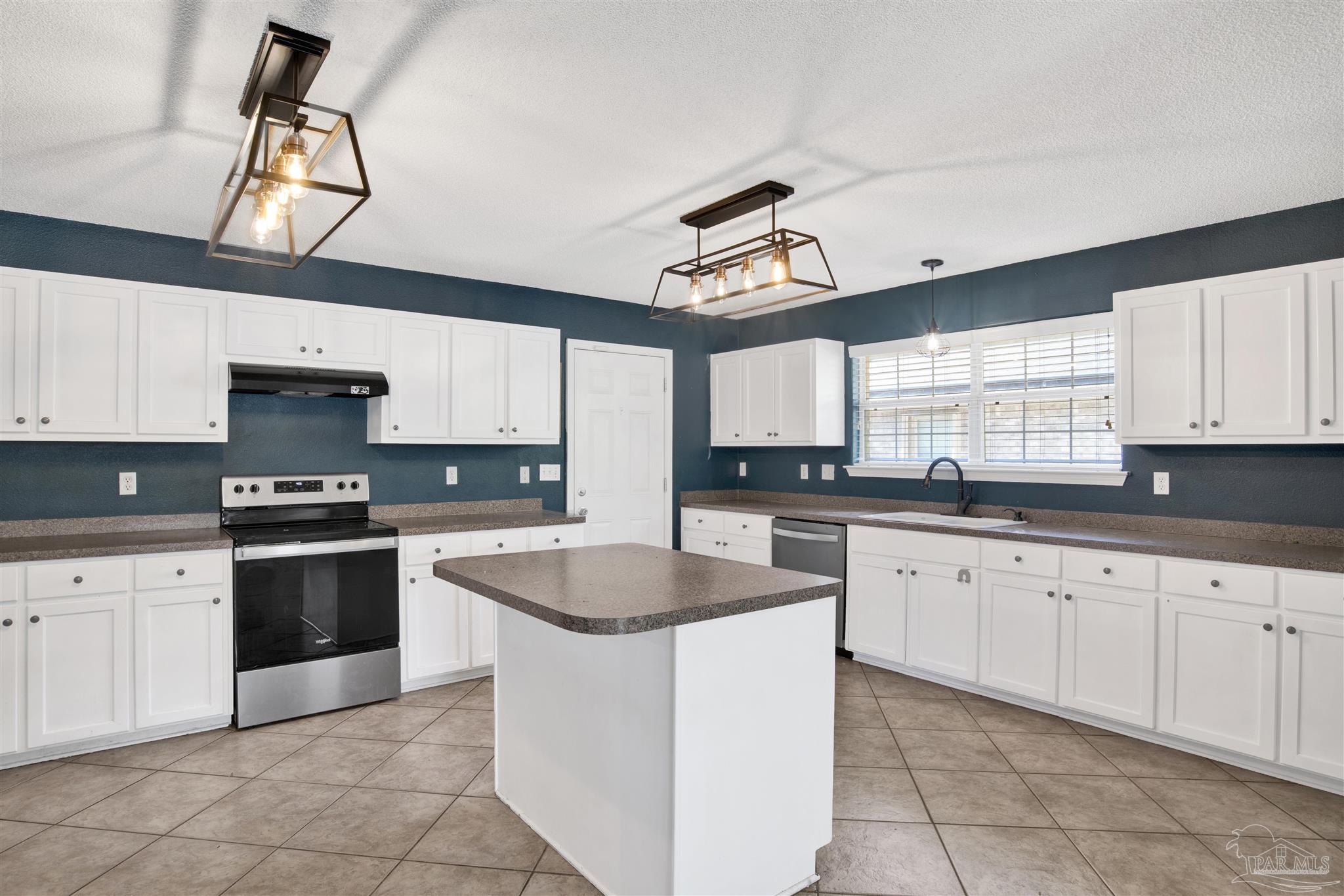 7604 Brewster Street Navarre, FL 32566 - Photo 19 of 36 a kitchen with granite countertop white cabinets white appliances a sink and a window