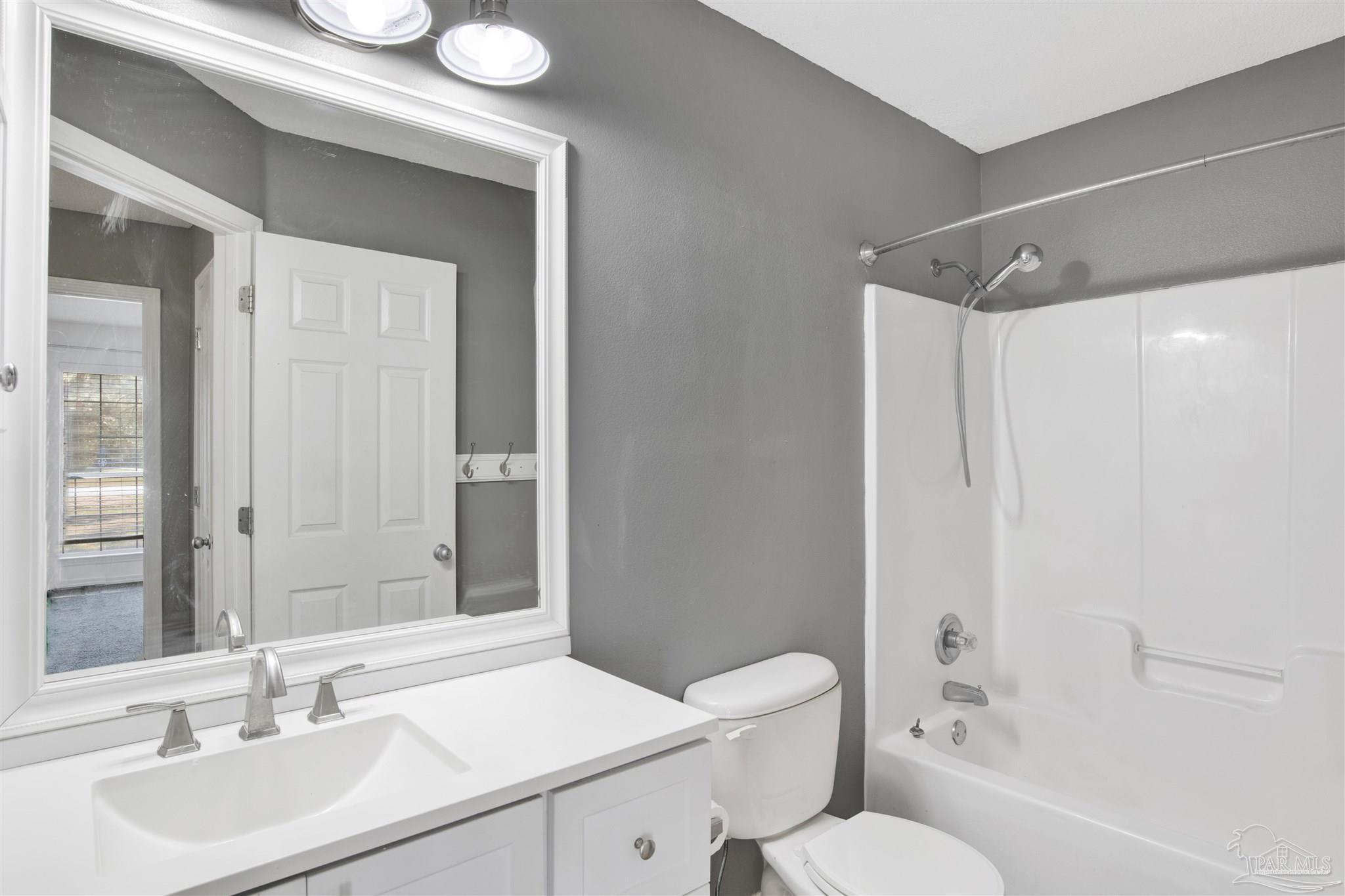 7604 Brewster Street Navarre, FL 32566 - Photo 31 of 36 a bathroom with a sink toilet vanity and shower