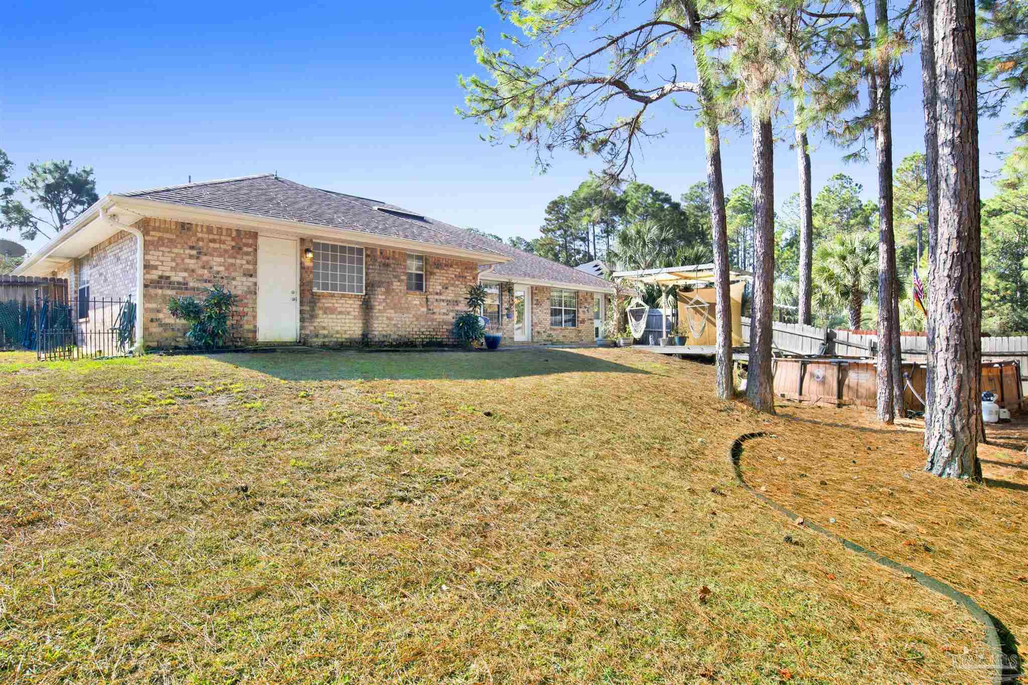 7604 Brewster Street Navarre, FL 32566 - Photo 5 of 36 a view of a house with a yard and potted plants