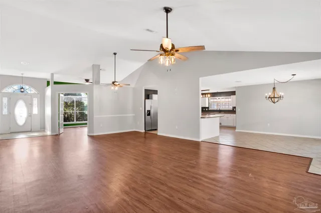 a view of a room with wooden floor a ceiling fan and windows