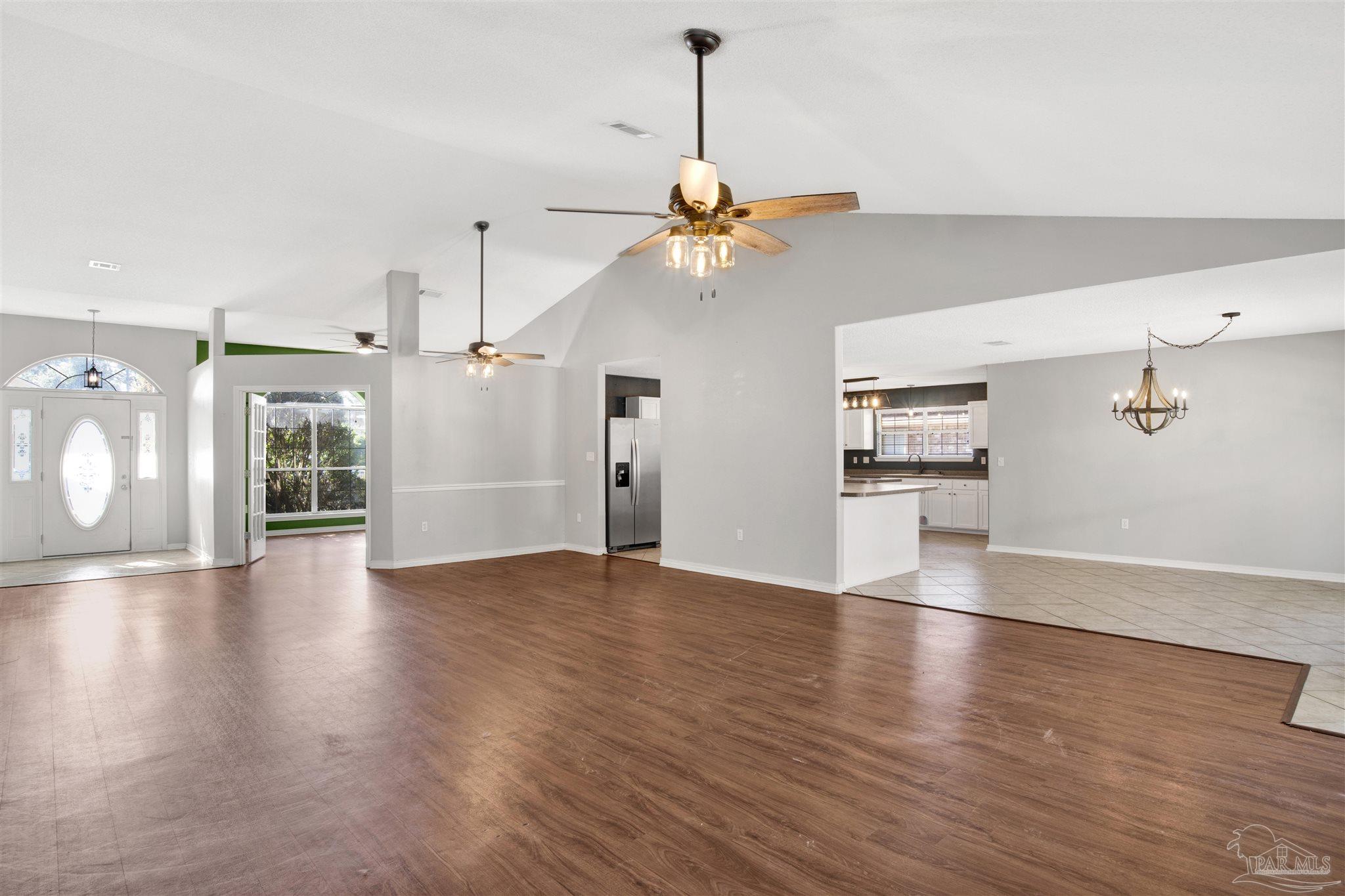 7604 Brewster Street Navarre, FL 32566 - Photo 9 of 36 a view of a room with wooden floor a ceiling fan and windows