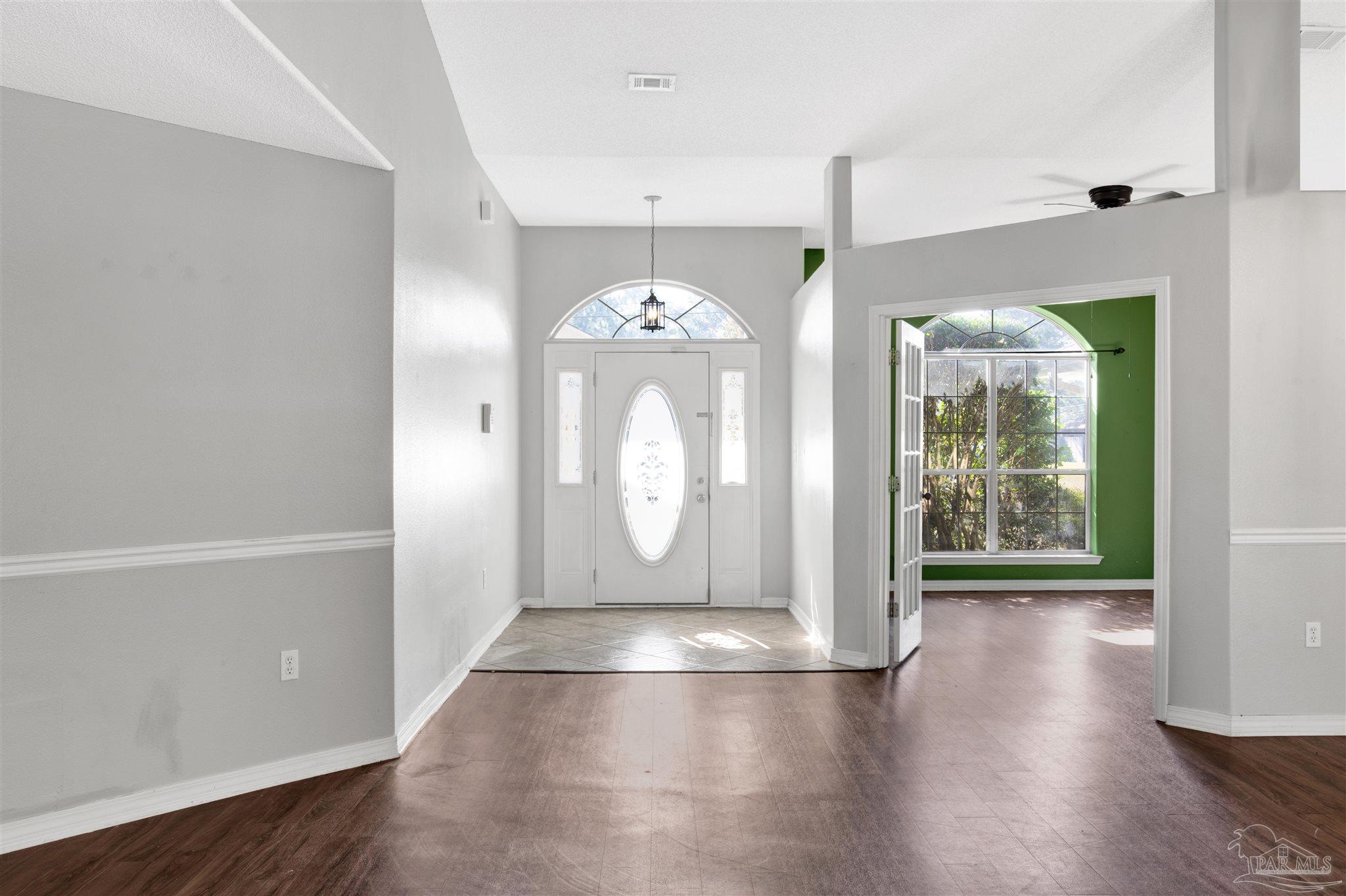 7604 Brewster Street Navarre, FL 32566 - Photo 10 of 36 an empty room with wooden floor and windows