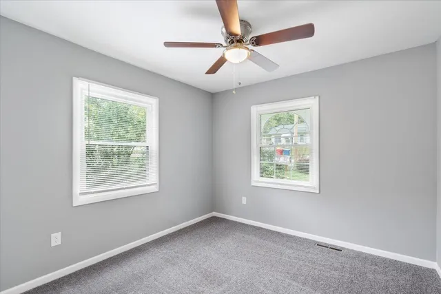 an empty room with a window and a fan