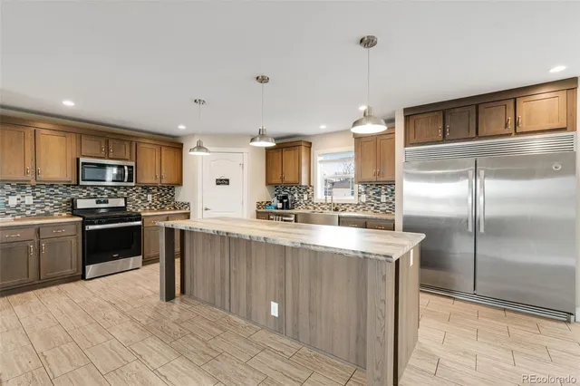 a large kitchen with kitchen island a large counter top stainless steel appliances and cabinets