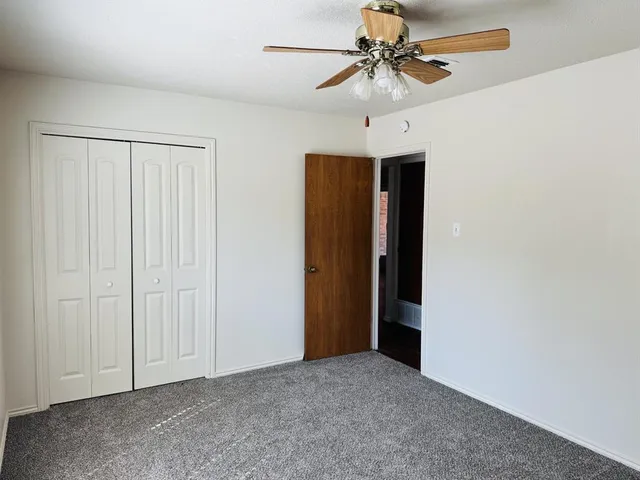an empty room with a ceiling fan and a window