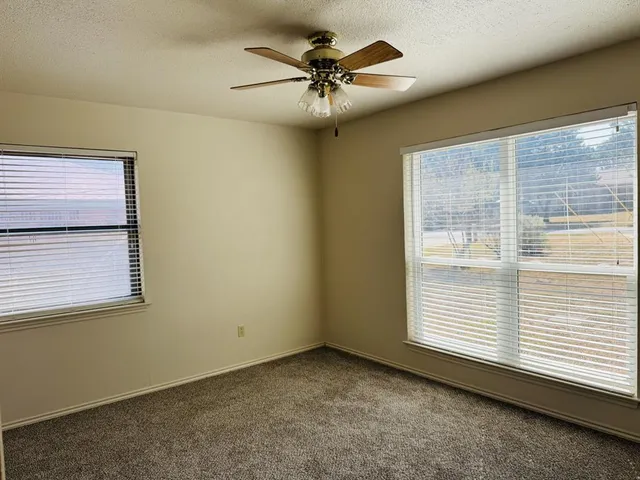 an empty room with a ceiling fan and windows