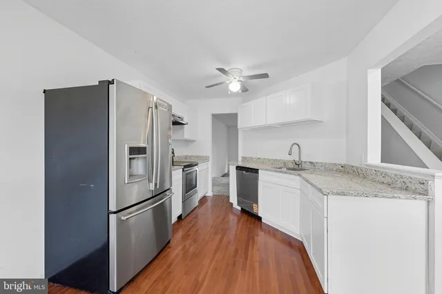 a kitchen with granite countertop a refrigerator stove and sink