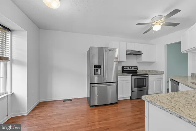 a kitchen with granite countertop a refrigerator oven a sink and dishwasher