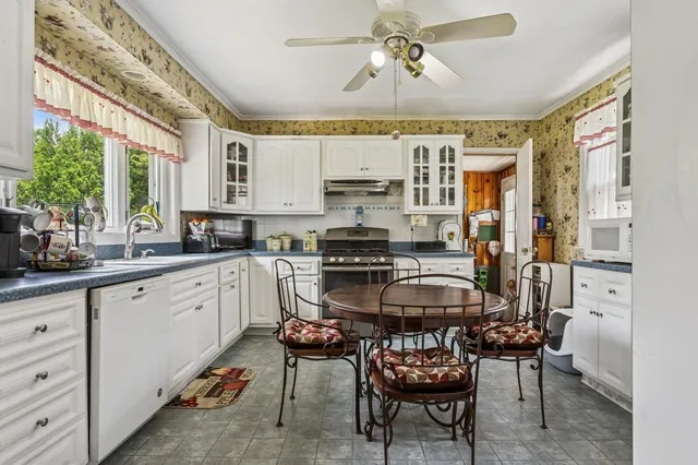 a kitchen with stainless steel appliances a stove a sink dishwasher a dining table and chairs with wooden floor