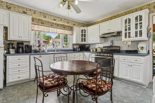 a kitchen with stainless steel appliances kitchen island granite countertop a table chairs sink and cabinets