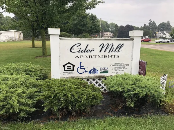 a sign of golf club on a wall under a tree