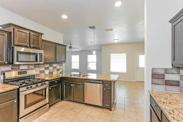 a kitchen with stainless steel appliances granite countertop a sink stove and refrigerator