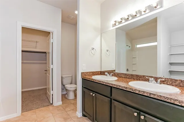 a bathroom with a granite countertop sink a toilet and a mirror