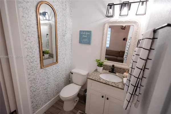 a bathroom with a granite countertop toilet a sink and a mirror