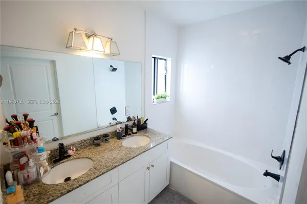 a bathroom with a granite countertop sink mirror and a bathtub