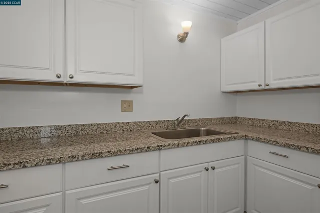 a kitchen with granite countertop white cabinets and a sink