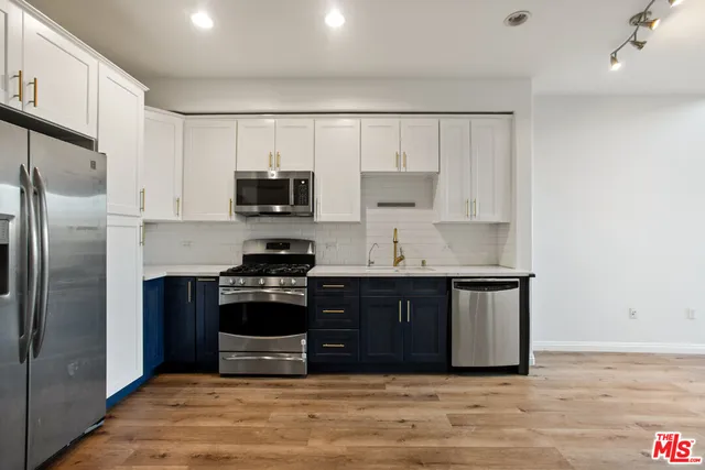 a kitchen with stainless steel appliances granite countertop a stove a refrigerator and a sink