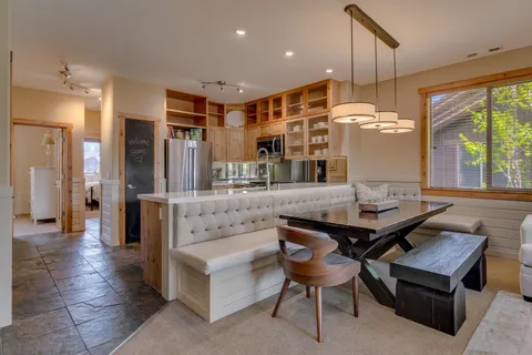 a kitchen with stainless steel appliances kitchen island granite countertop a table chairs and a refrigerator