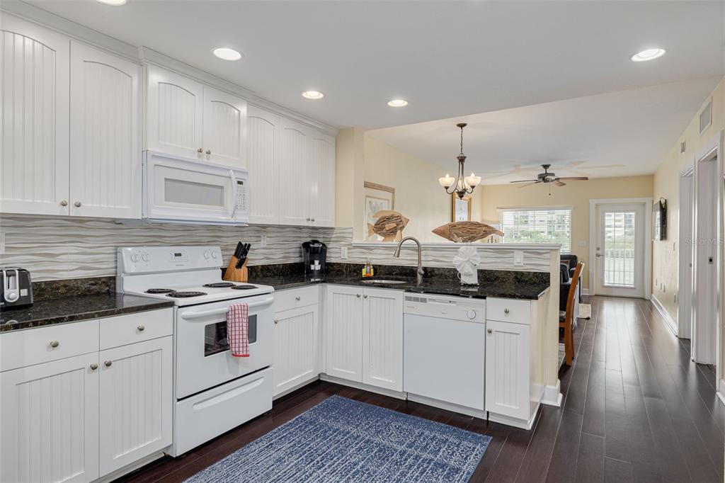 399 2nd Street, Unit 219 Indian Rocks Beach, FL 33785 - Photo 8 of 46 a kitchen with granite countertop white cabinets and white appliances