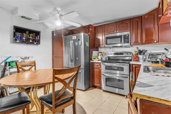 a kitchen with stainless steel appliances granite countertop a refrigerator a stove a sink a dining table and chairs with wooden floor