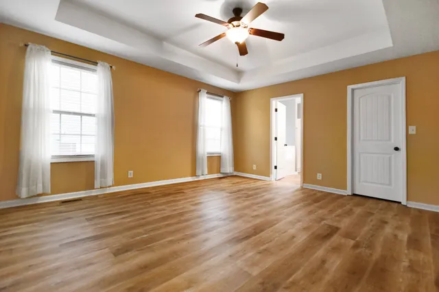 a view of an empty room with a window and wooden floor
