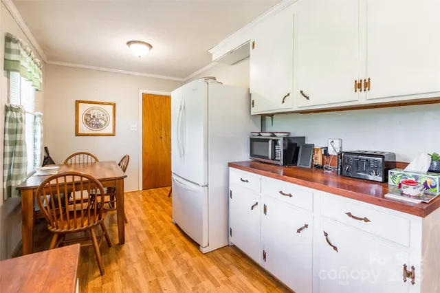 a kitchen with stainless steel appliances granite countertop a sink a stove a dining table and chairs with wooden floor
