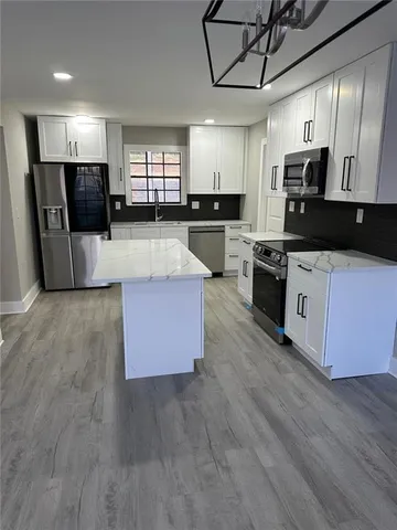 a large kitchen with stainless steel appliances granite countertop a stove a sink dishwasher and a refrigerator with wooden floor