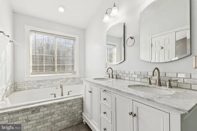 a bathroom with a granite countertop sink mirror and a bathtub