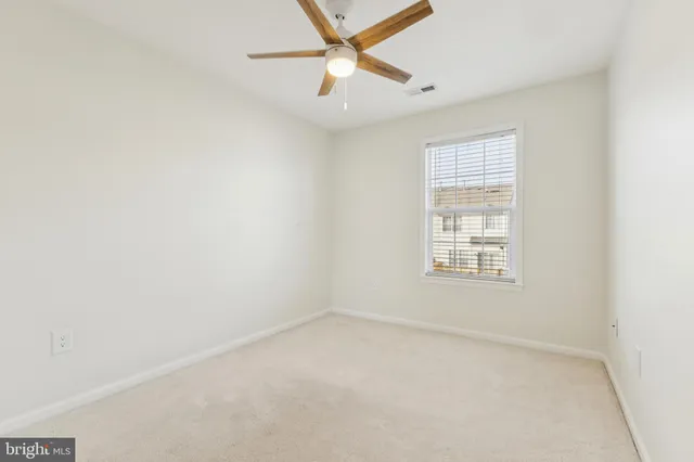 an empty room with a window and a ceiling fan