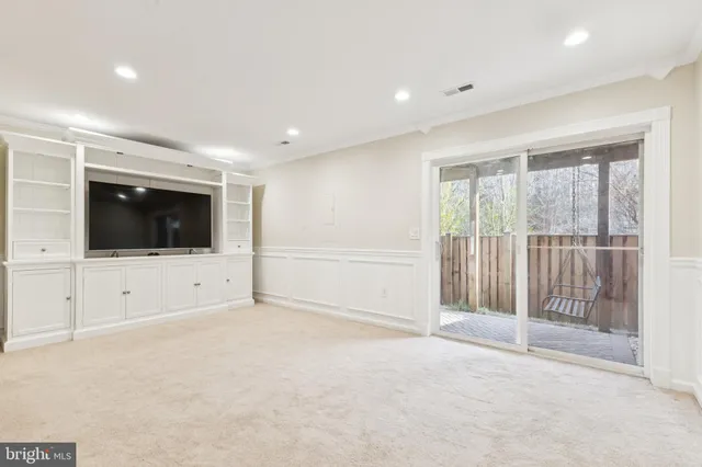 a view of an empty room with wooden floor and windows