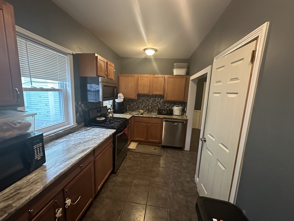 48 E Street Lowell, MA 01851 - Photo 5 of 14 a kitchen with granite countertop a refrigerator a sink a stove a microwave and island