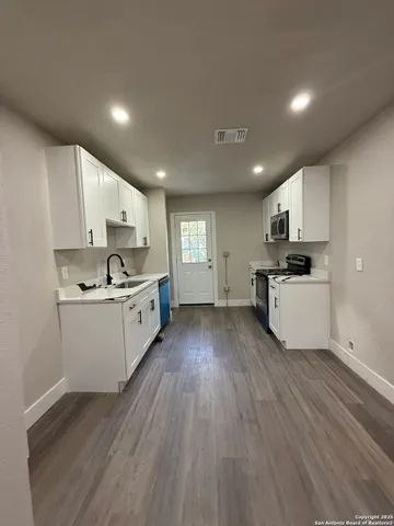 a kitchen with stove cabinets wooden floor and stainless steel appliances
