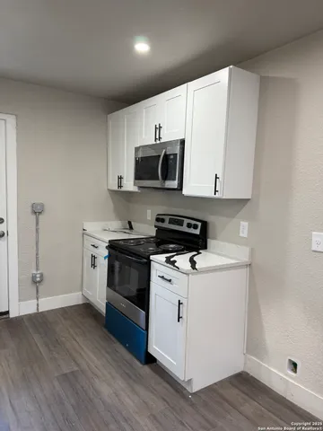 a kitchen with stainless steel appliances a stove a microwave and white cabinets