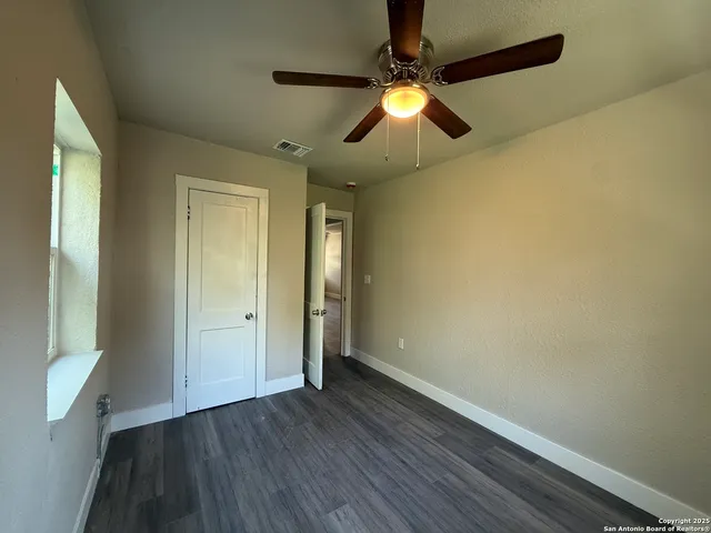 an empty room with wooden floor fan and window