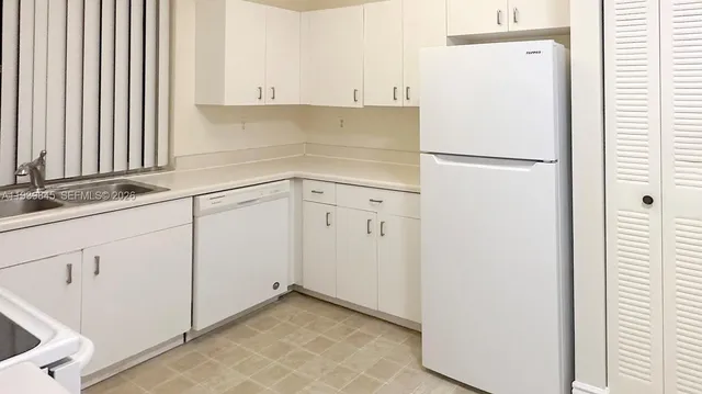 a kitchen with white cabinets and refrigerator
