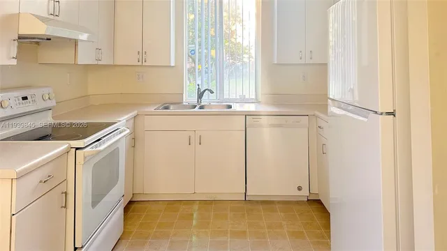 a kitchen with white cabinets and white appliances