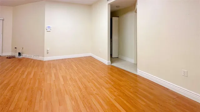 an empty room with wooden floor and a sink