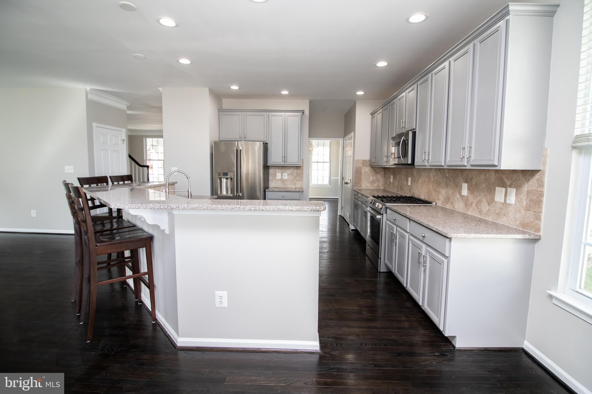 25257 Doolittle Lane Chantilly, VA 20152 - Photo 11 of 52 a kitchen with stainless steel appliances kitchen island granite countertop a stove a sink a refrigerator and white cabinets with wooden floor