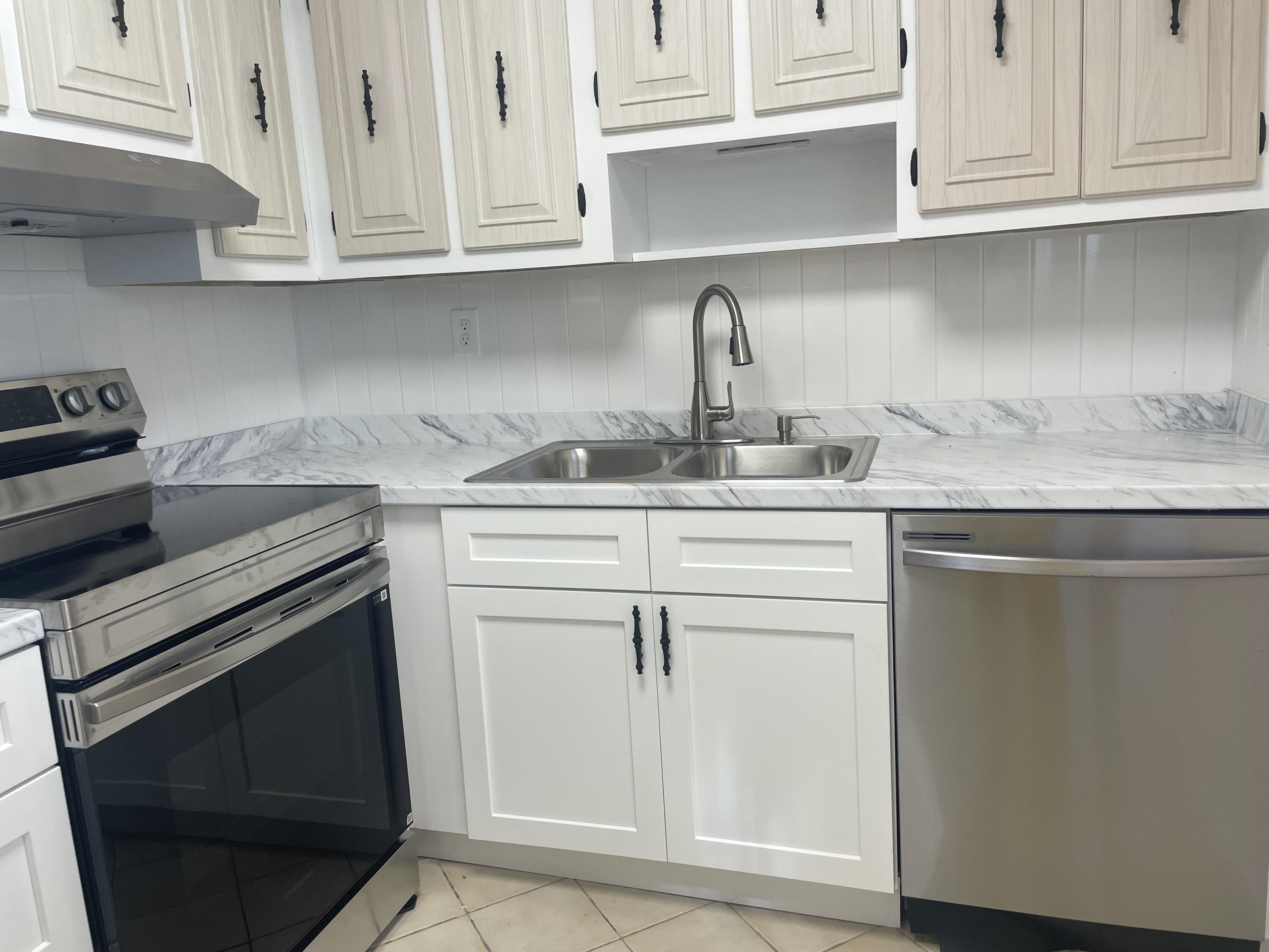 402 Monaco Way, Unit I Delray Beach, FL 33446 - Photo 2 of 25 a kitchen with white cabinets and appliances