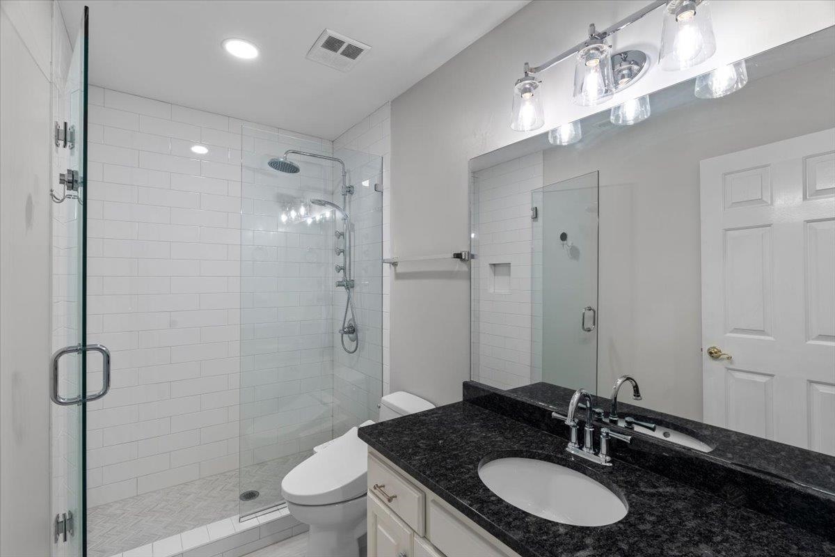 10440 Ansley Cove Collierville, TN 38017 - Photo 31 of 40 a bathroom with a granite countertop sink a toilet a mirror and shower