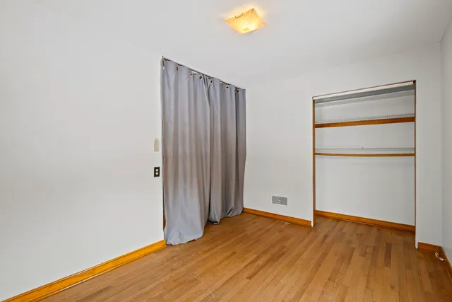 an empty room with wooden floor and closet