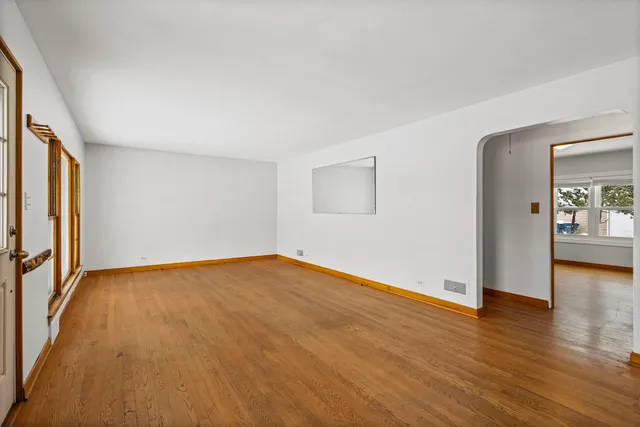 an empty room with wooden floor and natural light
