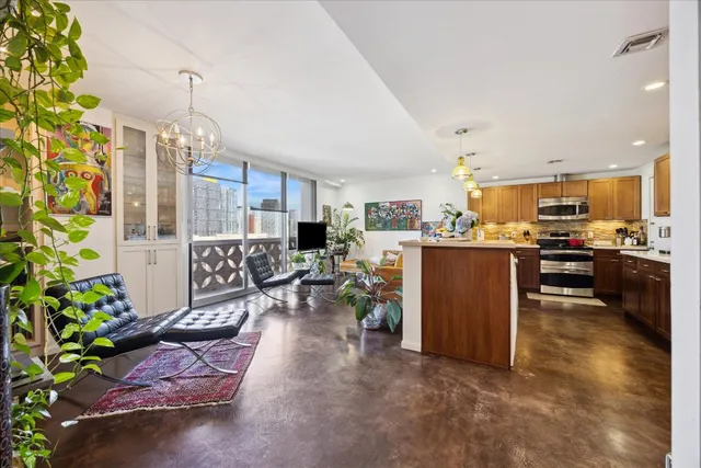 a living room with furniture a chandelier and kitchen view