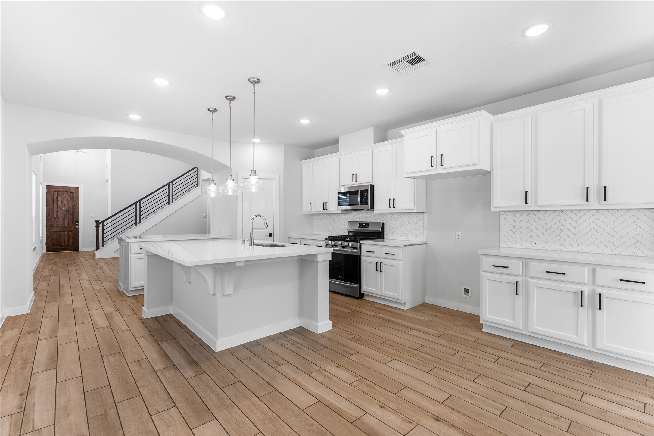 a kitchen with white cabinets stainless steel appliances and wooden floor