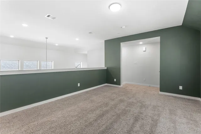 a view of an empty room with kitchen and a window