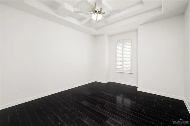 an empty room with wooden floor fan and window