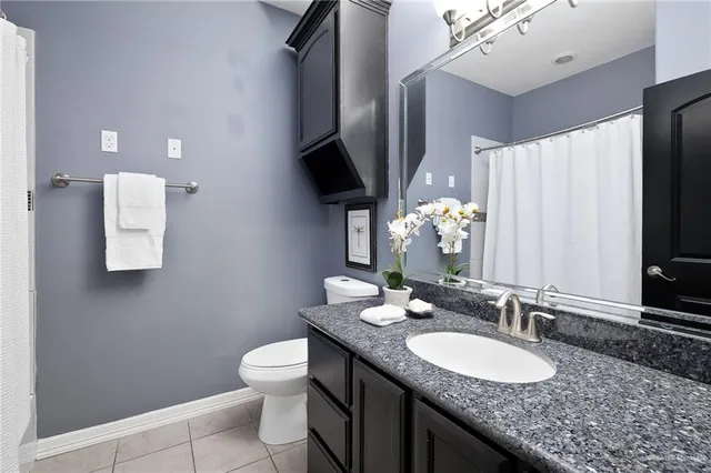 a bathroom with a granite countertop sink a toilet and a mirror
