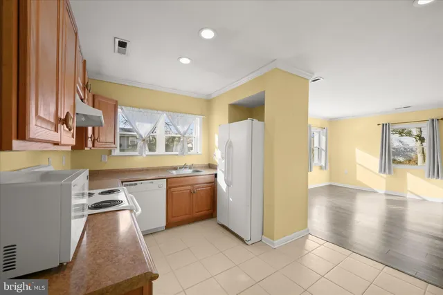 a kitchen with stainless steel appliances granite countertop a refrigerator a sink dishwasher and a stove with wooden floor